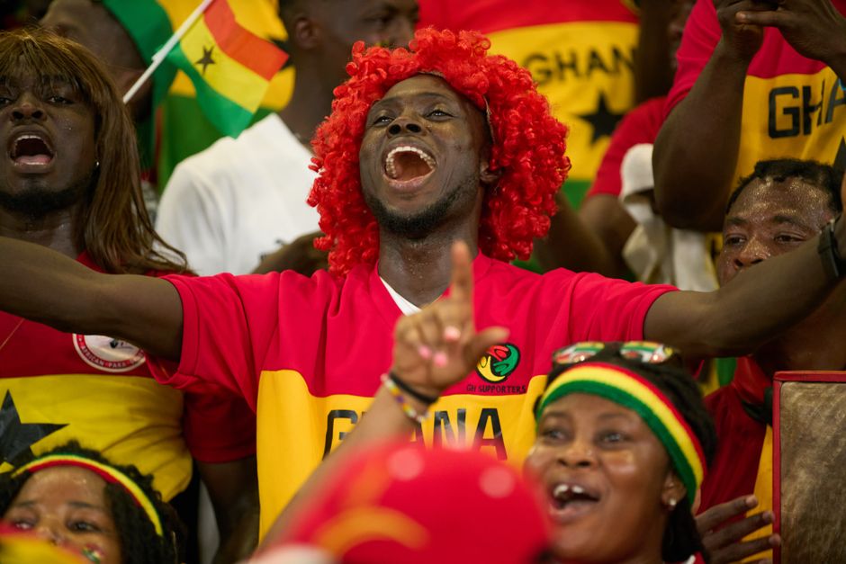 Ghanaian soccer fans passionately cheering during a match, showcasing national pride.