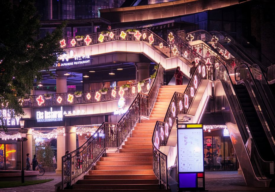 Colorful illuminated staircase in a lively Shanghai outdoor setting at night.